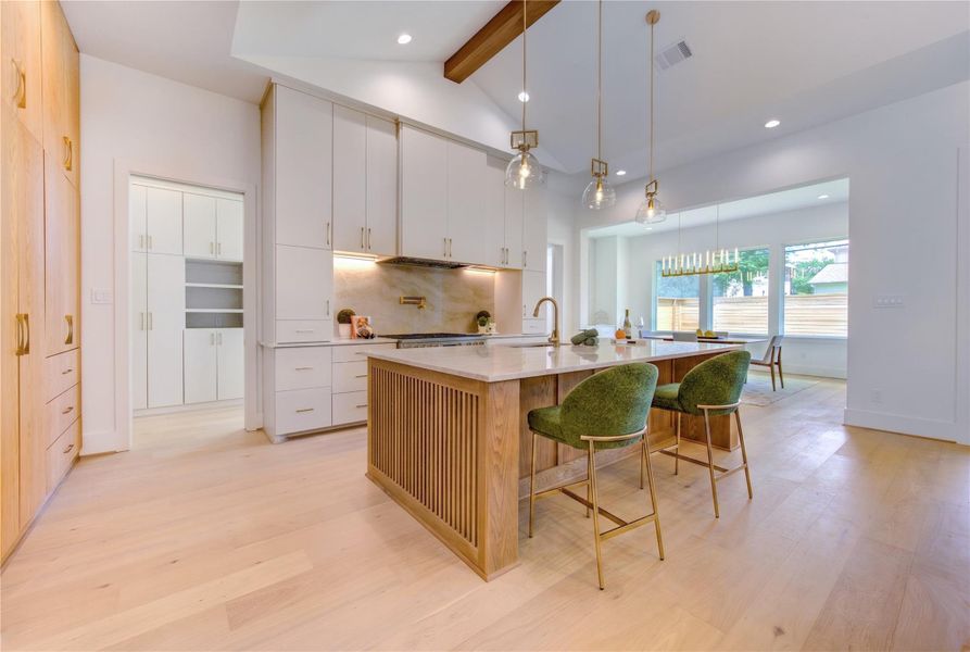 The chef’s kitchen showcases an oversized island, custom cabinetry, Taj Mahal Quartzite counters, premium appliances, and exquisite designer finishes.