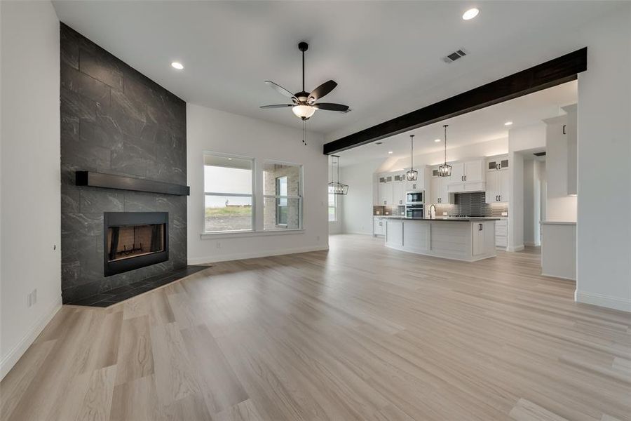 Unfurnished living room featuring ceiling fan, light hardwood / wood-style flooring, and a fireplace