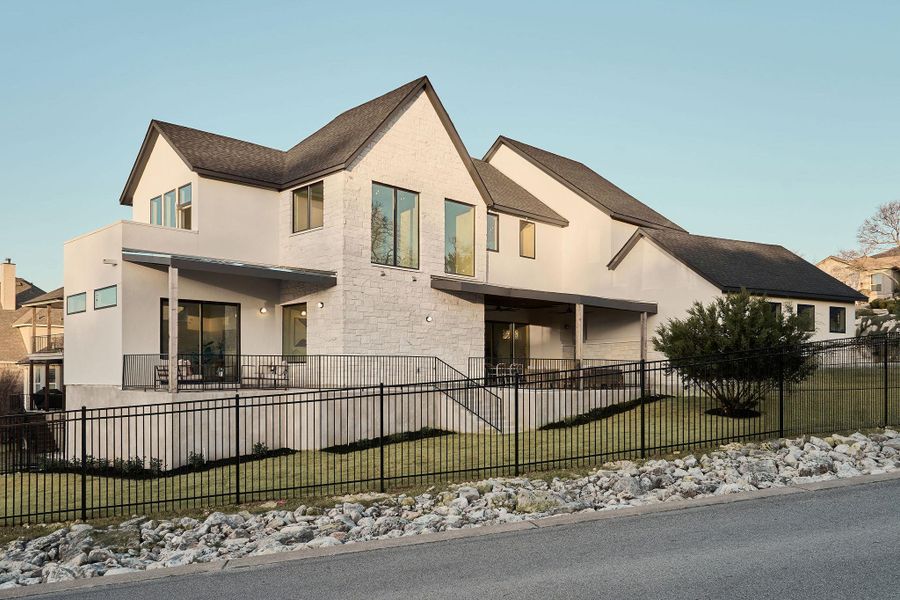 View of front of home with a fenced front yard, stone siding, and stucco siding