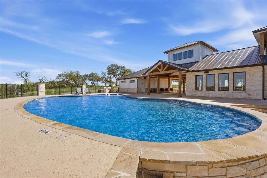 An inviting in-ground pool awaits, perfectly complemented by the adjacent outdoor kitchen and lounge area.