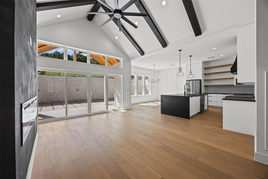 Unfurnished living room featuring a chandelier, light wood-type flooring, and a ceiling fan Unfurnished living room featuring a chandelier, light wood-type flooring, and a ceiling fan