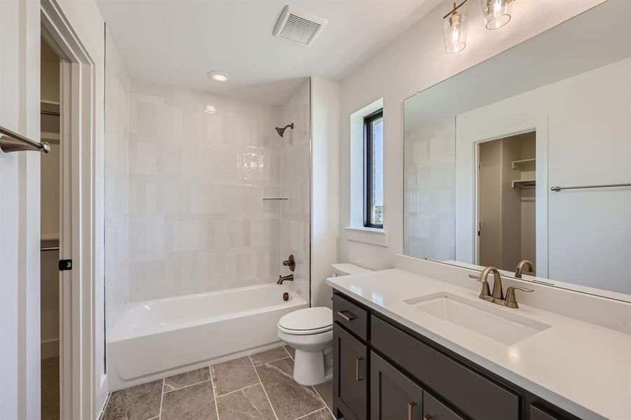 Full bathroom featuring tiled shower / bath, vanity, and toilet