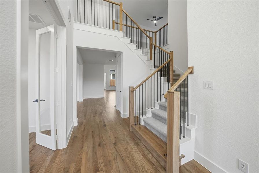 Stairs featuring wood finished floors and a high ceiling Stairs featuring wood finished floors and a high ceiling