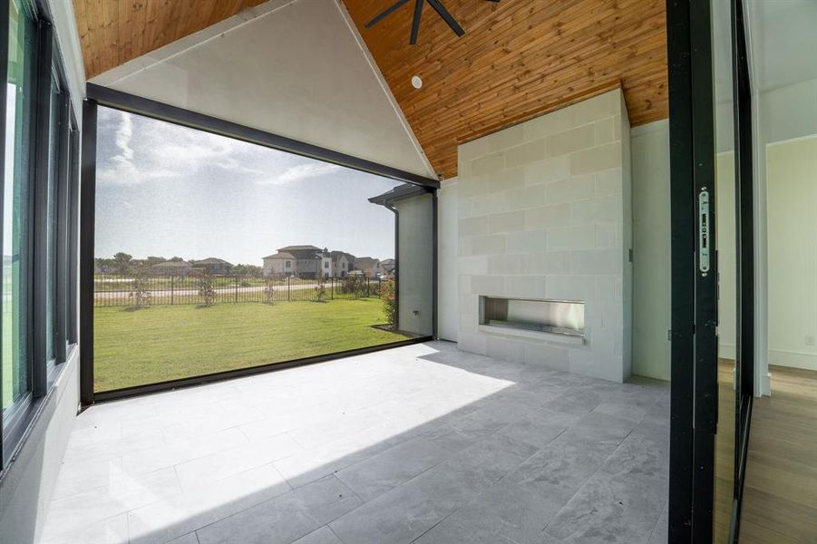 Unfurnished sunroom with wood ceiling, a tiled fireplace, and lofted ceiling