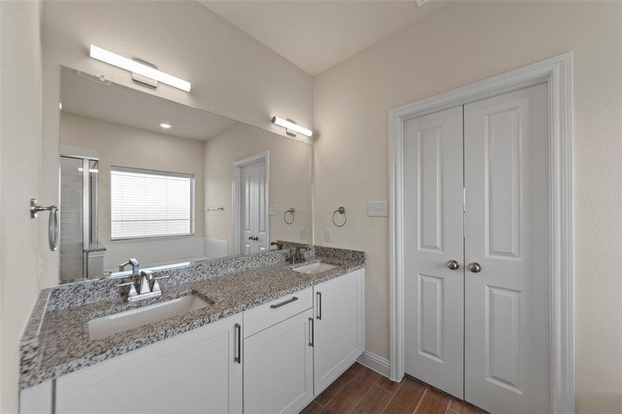 Bathroom with double vanity, wood finish floors, a shower stall, and a bath