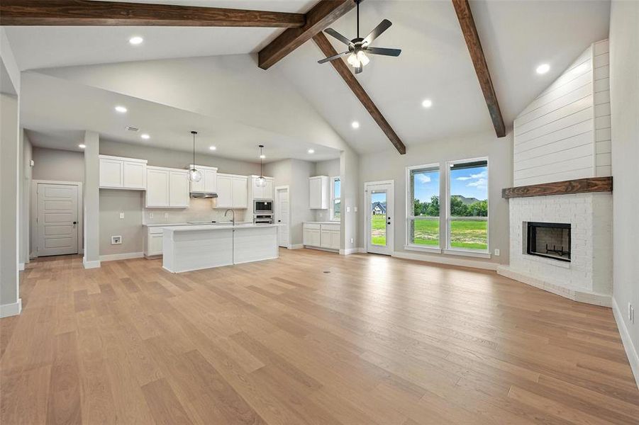 Unfurnished living room with ceiling fan, beamed ceiling, recessed lighting, a fireplace, and light wood-style flooring Unfurnished living room with ceiling fan, beamed ceiling, recessed lighting, a fireplace, and light wood-style flooring