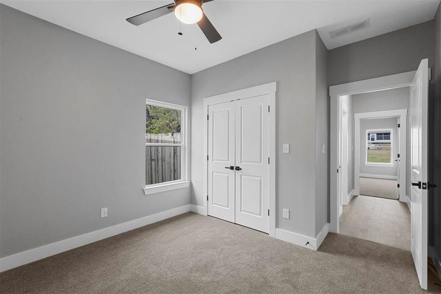 Unfurnished bedroom featuring light carpet, ceiling fan, and a closet