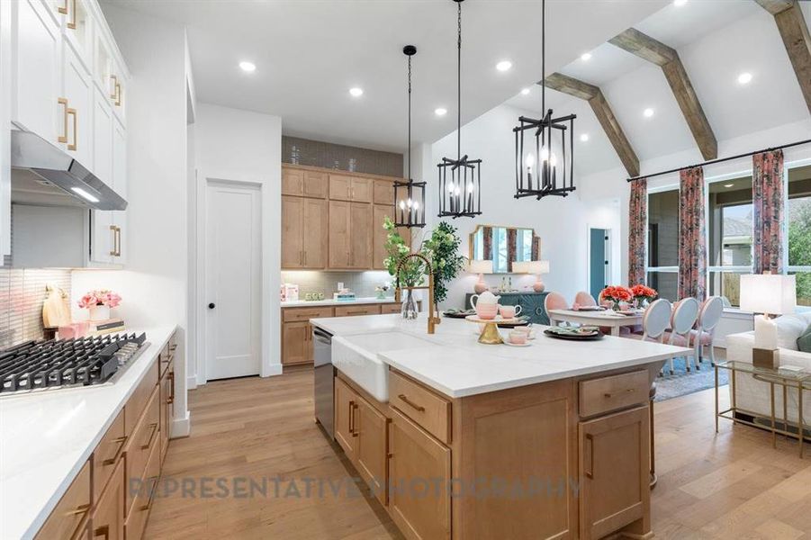 Kitchen with hanging light fixtures, open floor plan, light wood-style floors, a kitchen island with sink, and appliances with stainless steel finishes
