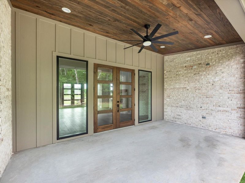 Private covered patio with wood-paneled ceiling and serene wooded views.