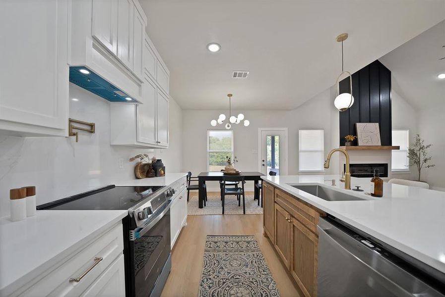 Kitchen with stainless steel appliances, recessed lighting, light wood-type flooring, white cabinets, and decorative light fixtures Kitchen with stainless steel appliances, recessed lighting, light wood-type flooring, white cabinets, and decorative light fixtures