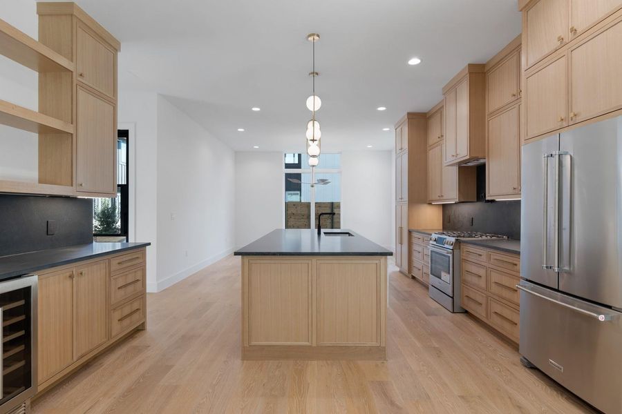 Kitchen with light brown cabinetry, appliances with stainless steel finishes, an island with sink, plenty of natural light, and tasteful backsplash Kitchen with light brown cabinetry, appliances with stainless steel finishes, an island with sink, plenty of natural light, and tasteful backsplash