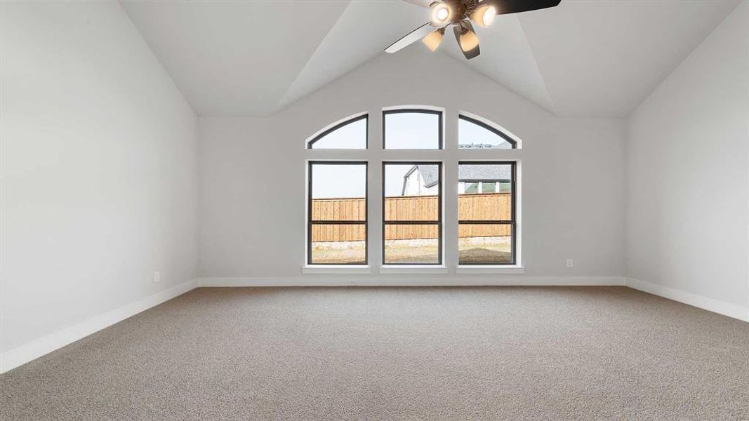 Empty room with vaulted ceiling, carpet flooring, and ceiling fan