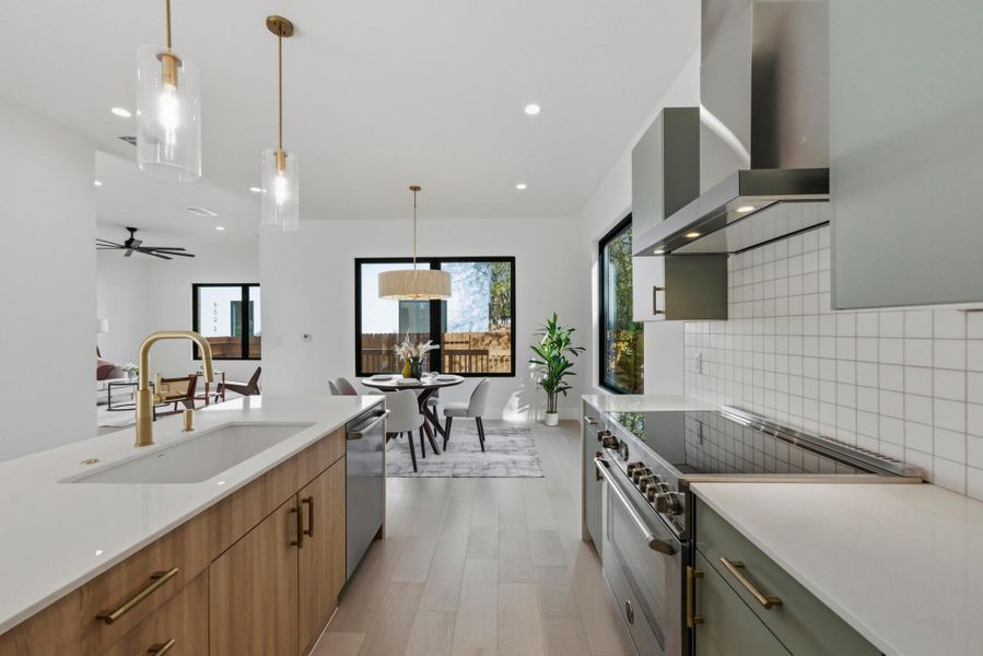 Kitchen with appliances with stainless steel finishes, pendant lighting, tasteful backsplash, wall chimney range hood, and recessed lighting