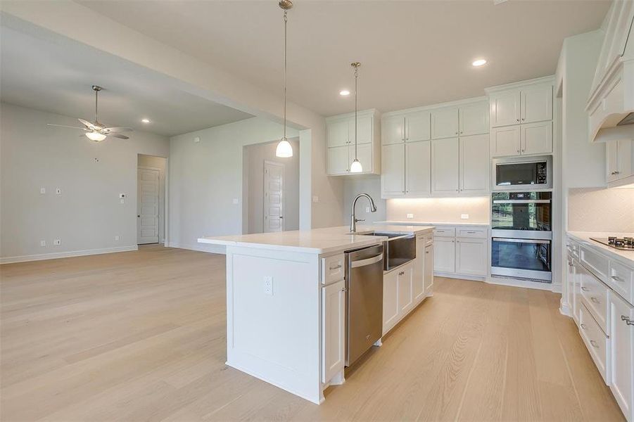 Kitchen with ceiling fan, light hardwood / wood-style flooring, sink, a center island with sink, and stainless steel appliances