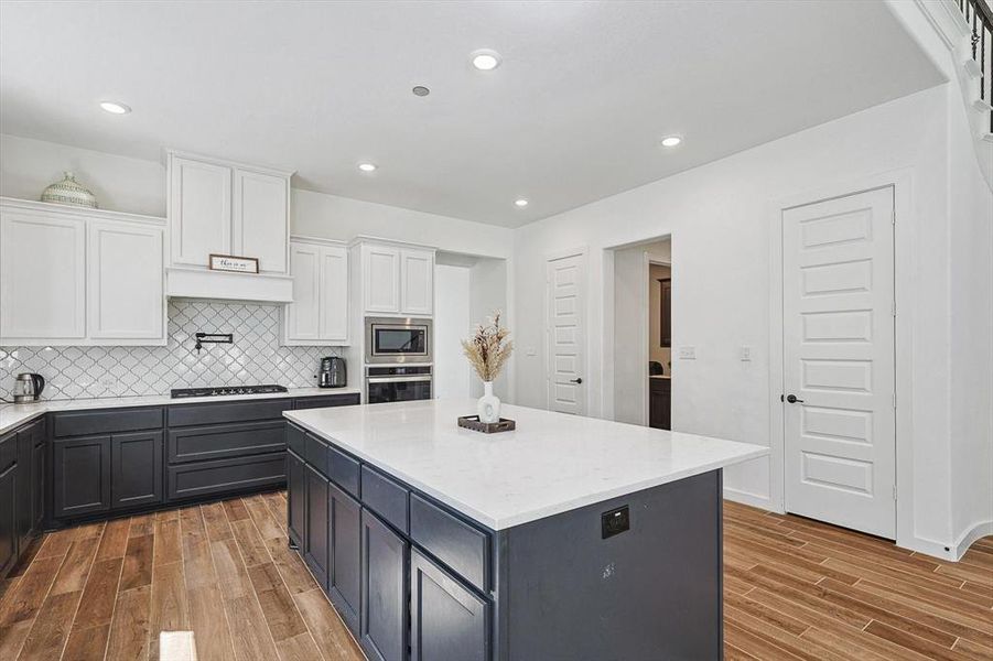 Kitchen with white cabinets, appliances with stainless steel finishes, and light hardwood / wood-style flooring