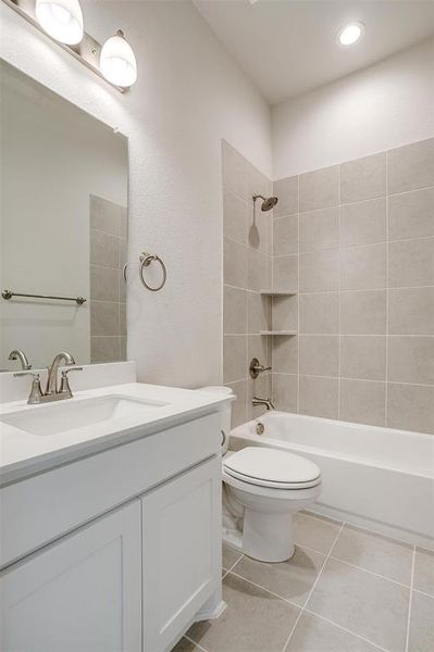 Full bathroom featuring tile patterned floors, vanity, tiled shower / bath combo, and toilet