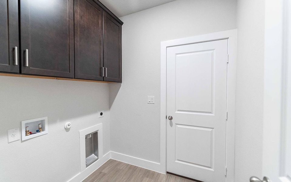 Clothes washing area featuring hookup for a washing machine, hookup for a gas dryer, hookup for an electric dryer, light wood-type flooring, and cabinet space
