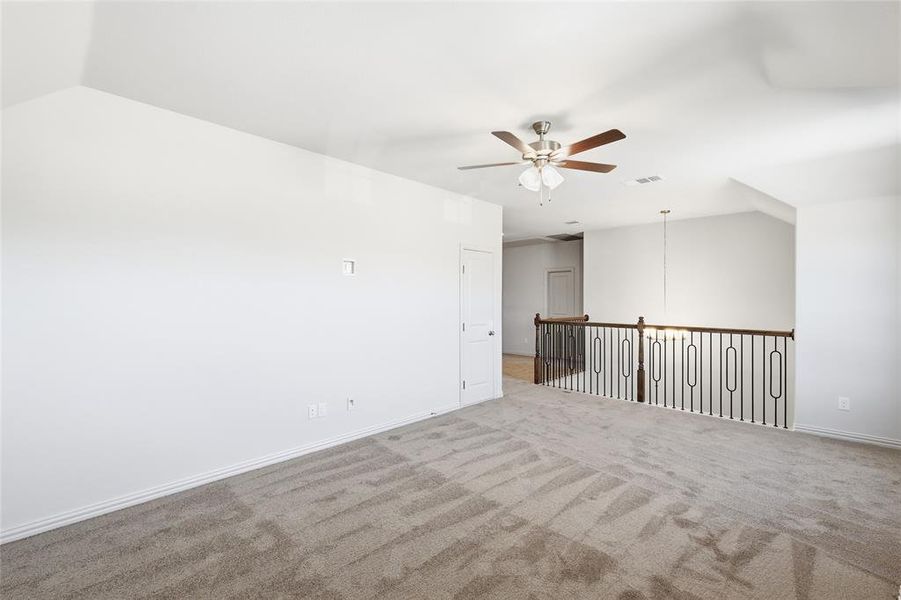 Unfurnished room featuring carpet floors, ceiling fan, and vaulted ceiling
