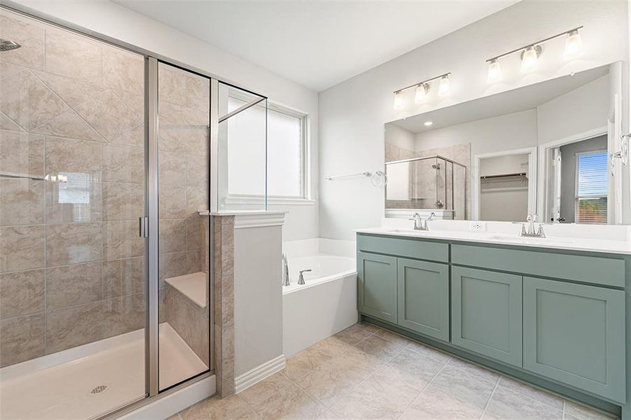 Full bathroom with double vanity, a shower stall, a garden tub, a walk in closet, and light tile patterned flooring Full bathroom with double vanity, a shower stall, a garden tub, a walk in closet, and light tile patterned flooring