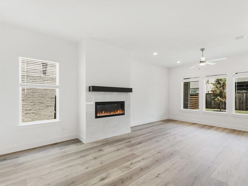 Unfurnished living room featuring light wood-style flooring, a tiled fireplace, recessed lighting, and ceiling fan