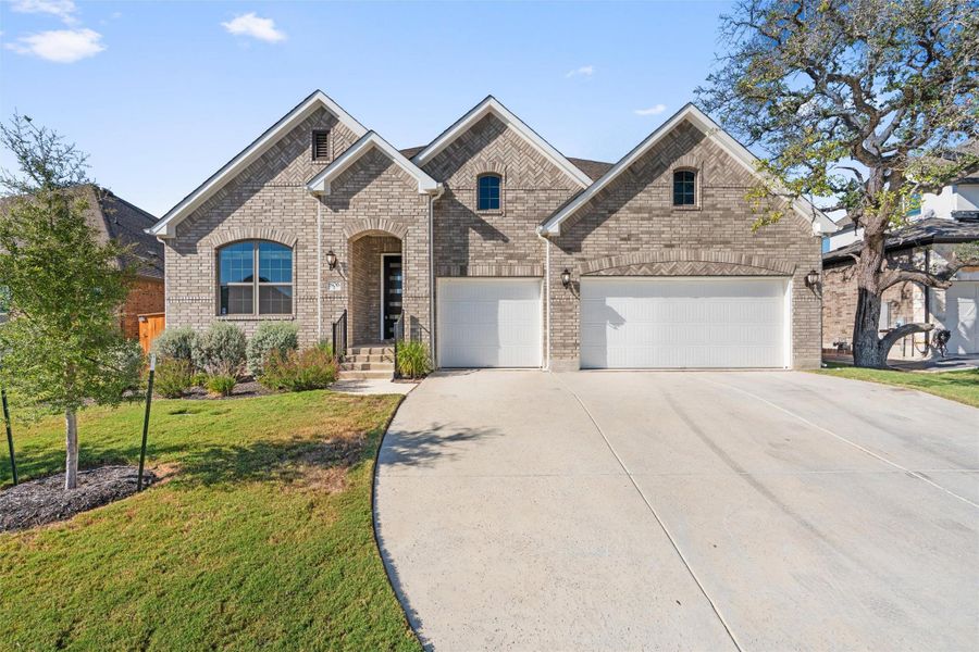 French provincial home featuring concrete driveway, brick siding, a front yard, and a garage