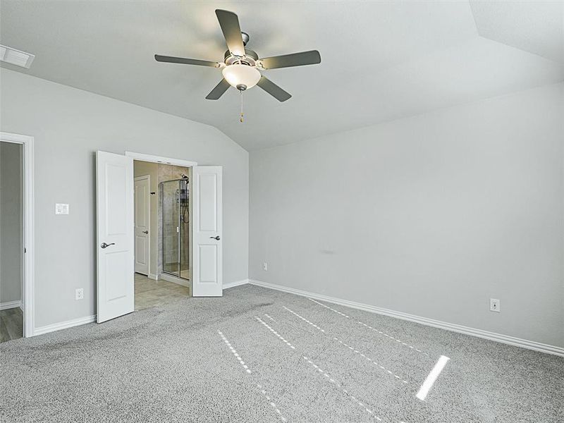 Unfurnished bedroom featuring ceiling fan, light carpet, and vaulted ceiling