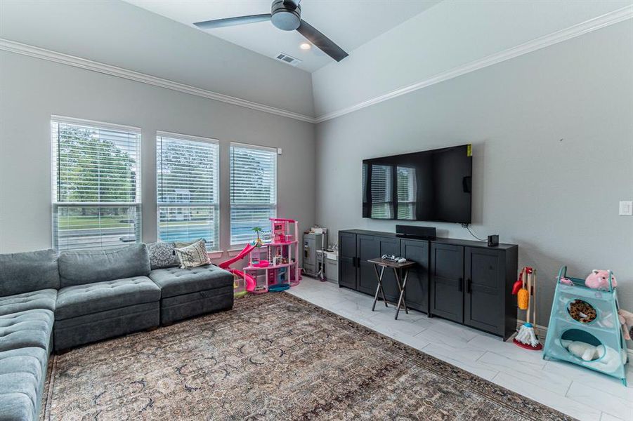 Living room featuring a ceiling fan, lofted ceiling, crown molding, light marble finish flooring, and recessed lighting Living room featuring a ceiling fan, lofted ceiling, crown molding, light marble finish flooring, and recessed lighting