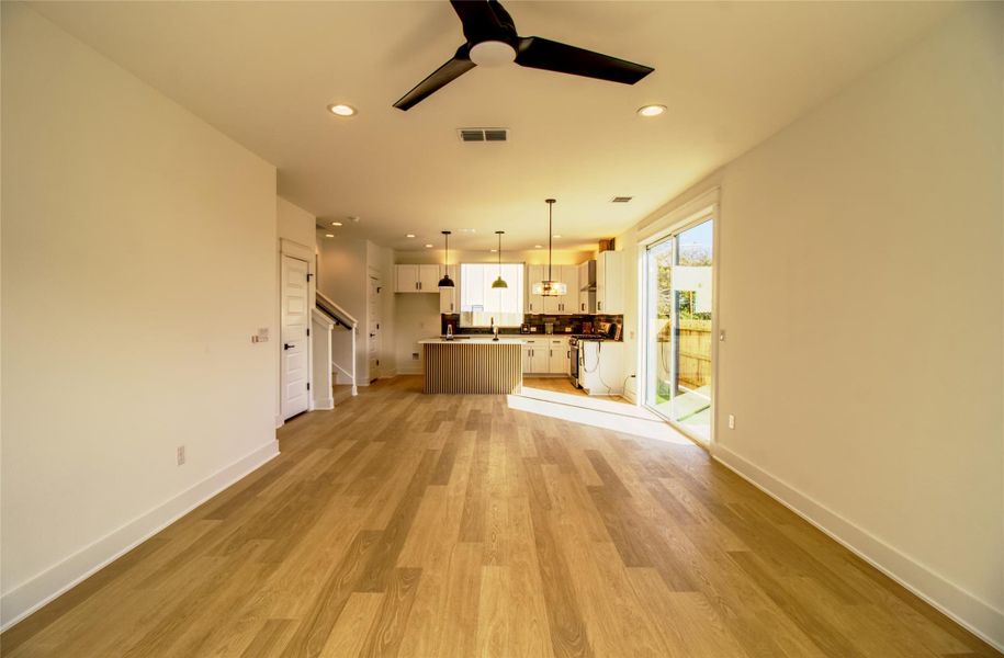 Unfurnished living room with light wood-type flooring, a ceiling fan, recessed lighting, and stairs