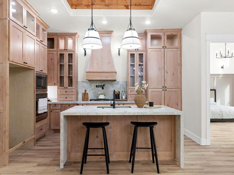 Kitchen with a kitchen breakfast bar, light stone countertops, glass insert cabinets, recessed lighting, and decorative backsplash