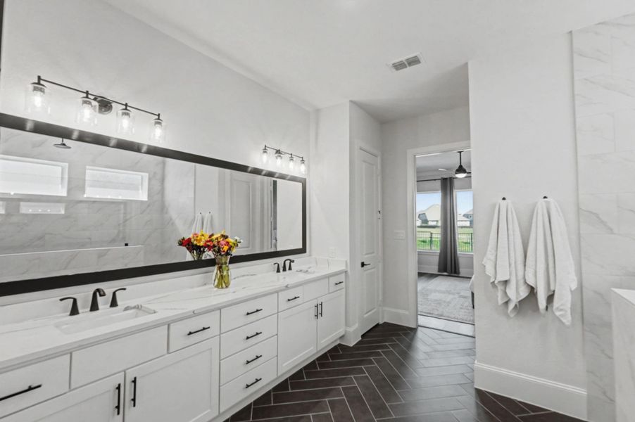 Spacious primary bath with double sinks, extended vanity, impressive mirror, and walk-in shower. Clean finishes and direct access to the bedroom.