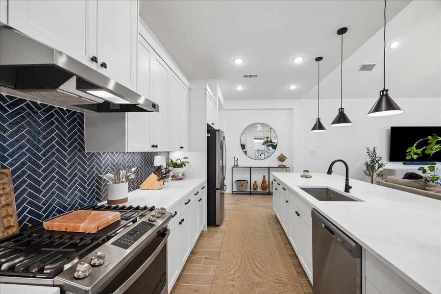 Modern gourmet kitchen highlighting a designer herringbone tile backsplash and sleek stainless steel vent hood. Enjoy the perfect blend of style and function with custom J-Kraft cabinetry, quartz countertops, and a large island designed for gathering. Modern gourmet kitchen highlighting a designer herringbone tile backsplash and sleek stainless steel vent hood. Enjoy the perfect blend of style and function with custom J-Kraft cabinetry, quartz countertops, and a large island designed for gathering.