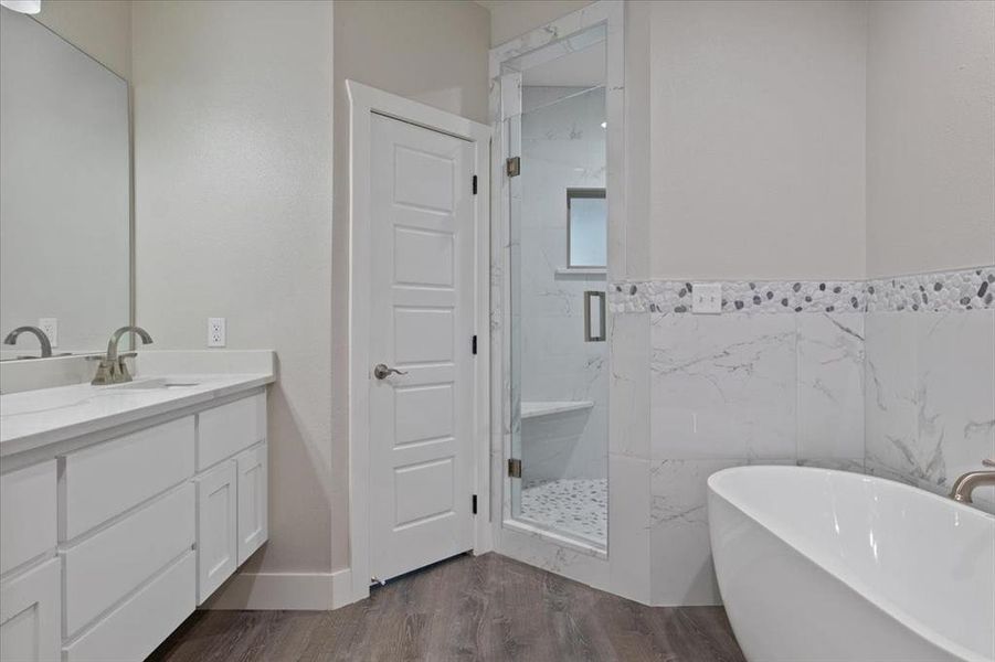 Bathroom with vanity, independent shower and bath, and hardwood / wood-style floors