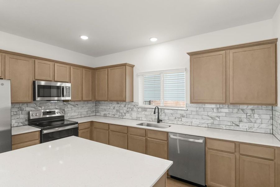 Kitchen featuring stainless steel appliances, light stone counters, decorative backsplash, and recessed lighting