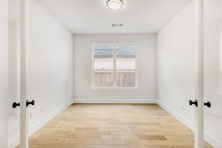 Bright room featuring wood-finish flooring, white baseboards, and a white ceiling with a flush-mount light fixture