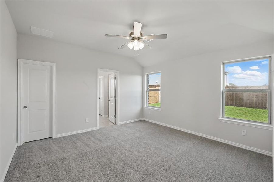 Unfurnished bedroom featuring carpet flooring, vaulted ceiling, ensuite bathroom, and ceiling fan Unfurnished bedroom featuring carpet flooring, vaulted ceiling, ensuite bathroom, and ceiling fan