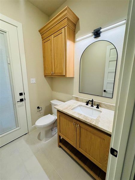 Bathroom with toilet, vanity, and tile patterned flooring