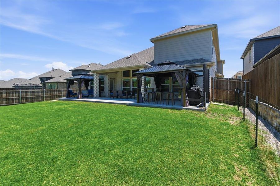 Spacious backyard featuring a large concrete patio, two covered gazebos, and a privacy fence