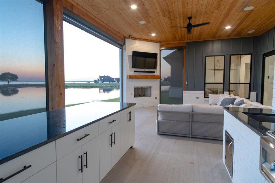View of patio with a water view, an outdoor living space with a fireplace, and a ceiling fan View of patio with a water view, an outdoor living space with a fireplace, and a ceiling fan