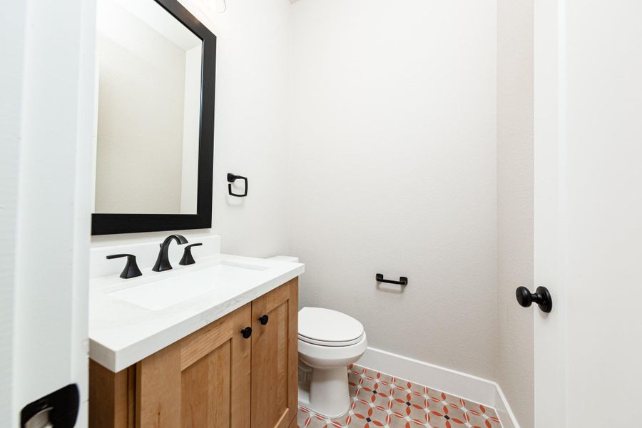 The powder bath features a stylish vanity with framed mirror, and a clean, modern design.