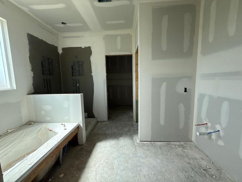 Bathroom under construction featuring a tub enclosure, shower area with backer board, and drywall-finished walls Bathroom under construction featuring a tub enclosure, shower area with backer board, and drywall-finished walls