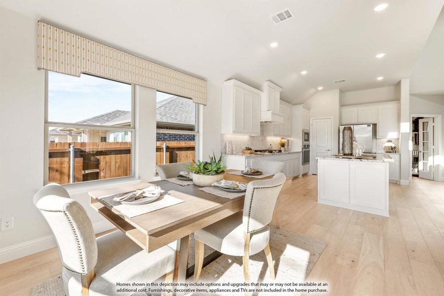 Open dining area with wood table flowing into white kitchen with island and hardwood floors Open dining area with wood table flowing into white kitchen with island and hardwood floors
