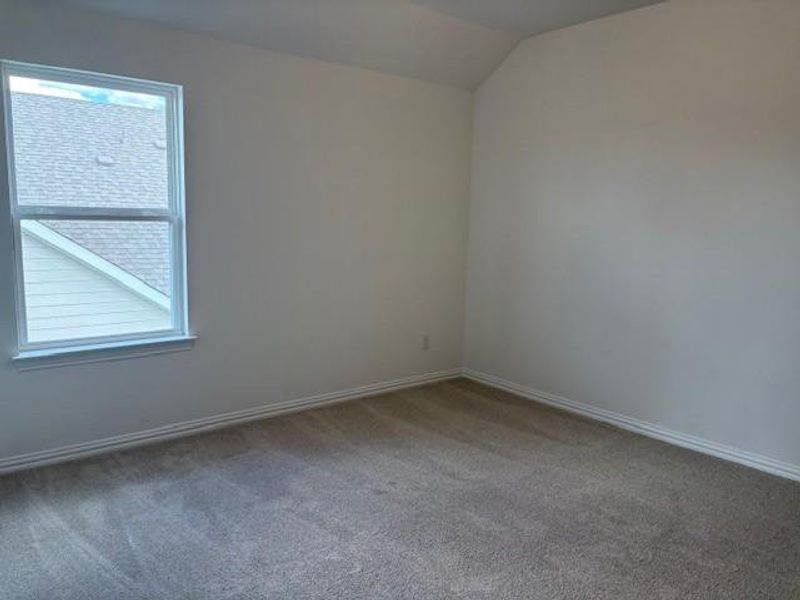 Carpeted empty room featuring baseboards and vaulted ceiling Carpeted empty room featuring baseboards and vaulted ceiling