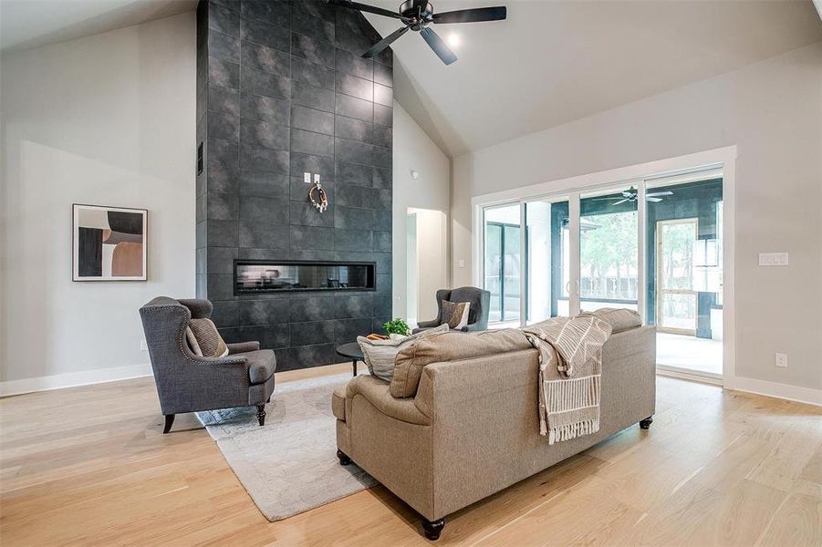 Living room featuring light wood finished floors, baseboards, a ceiling fan, and high vaulted ceiling Living room featuring light wood finished floors, baseboards, a ceiling fan, and high vaulted ceiling