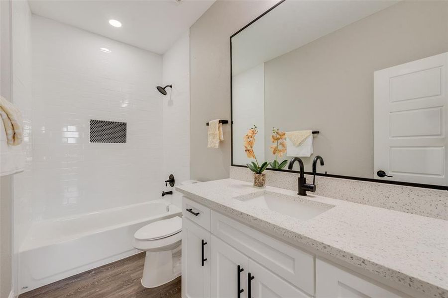 Full bathroom with tiled shower / bath combo, wood-type flooring, toilet, and vanity