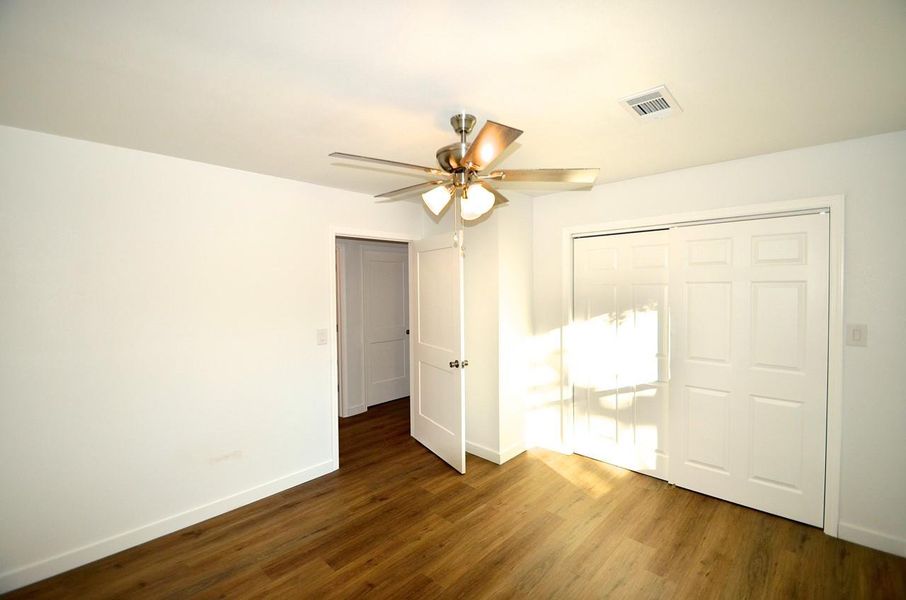 Unfurnished bedroom featuring dark wood-type flooring, a ceiling fan, and a closet