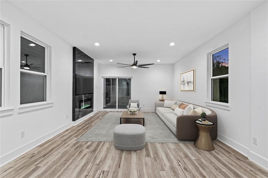 Living room with a fireplace, light wood-type flooring, and ceiling fan