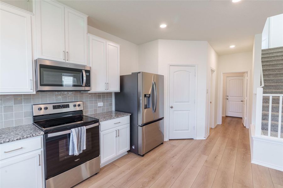 Granite counters and stainless steel appliances outfit this functional kitchen space, complementing the wood plank flooring and light cabinetry. Granite counters and stainless steel appliances outfit this functional kitchen space, complementing the wood plank flooring and light cabinetry.
