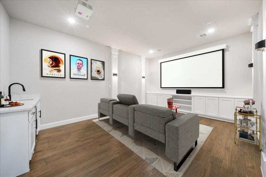 Cinema room with sink, dark wood-type flooring, and ornate columns