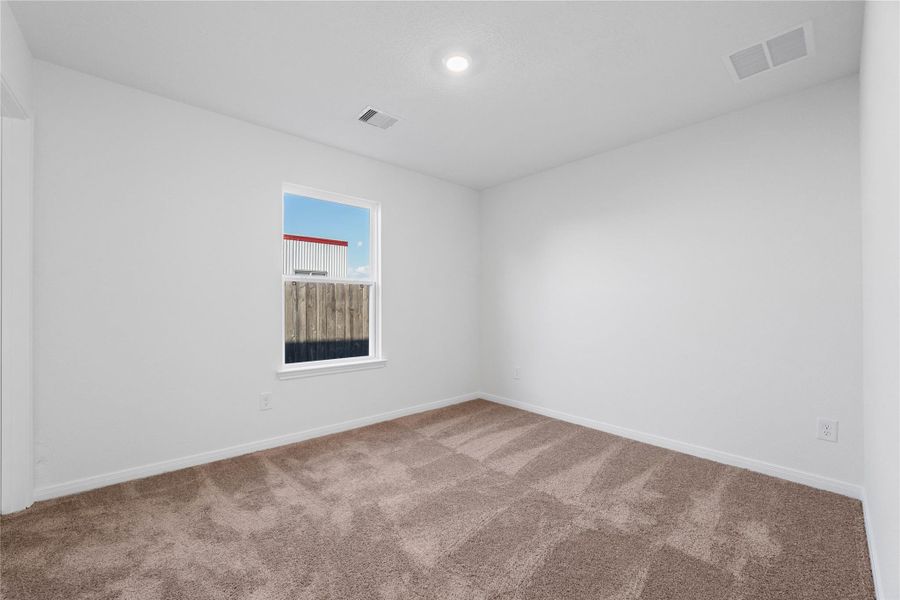 This secondary bedroom offers comfort and style with plush carpeting, neutral paint tones, recessed lighting, a large window, and a generously sized closet. This secondary bedroom offers comfort and style with plush carpeting, neutral paint tones, recessed lighting, a large window, and a generously sized closet.