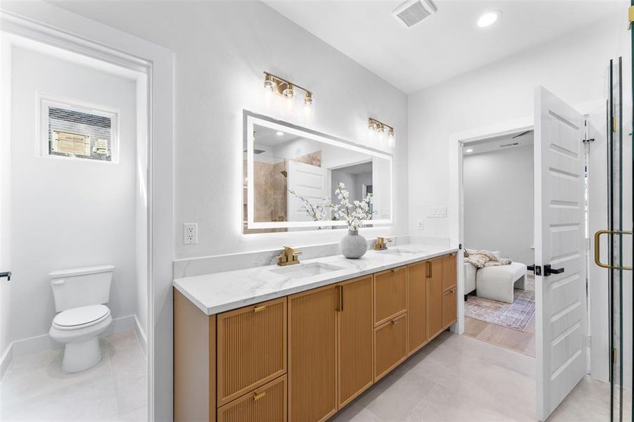 Ensuite bathroom with double vanity, a stall shower, light tile patterned floors, and recessed lighting